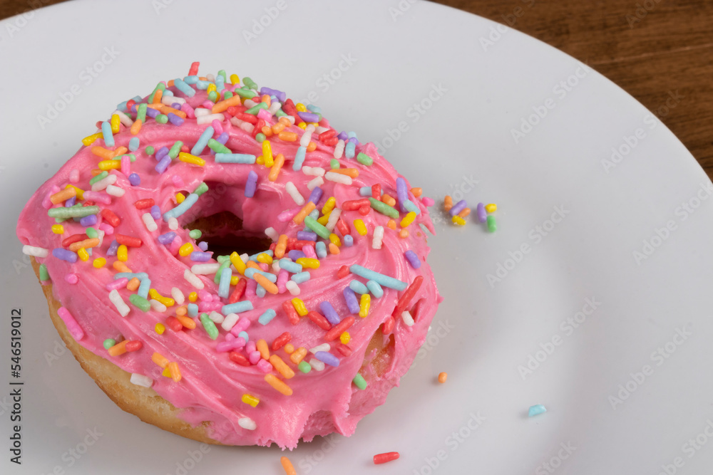 Sweet donuts with pink frosting and colorful sprinkles served on a plate. Sweet donuts with pink frosting and colorful sprinkles served on a plate.