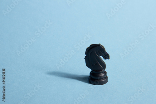 Business and leadership concept. Black chess knight on a blue background