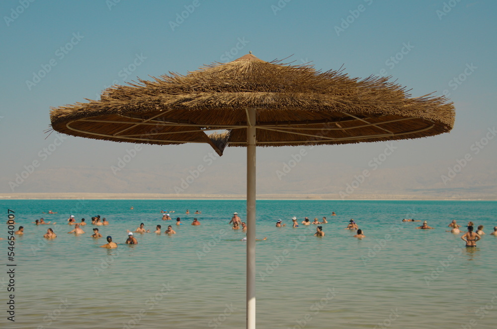 Resort on the Dead Sea. Beach, straw umbrellas, lifeguard houses, people bathe in salt water. health resort in Israel