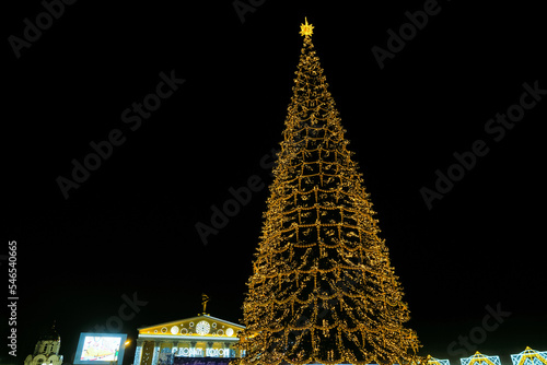 Belgorod, Russia - January 04, 2022: Sobornaya (Cathedral) Square with new year decorations and main lights fir-tree in the center of Belgorod city. Golden yellow mesh garland. photo