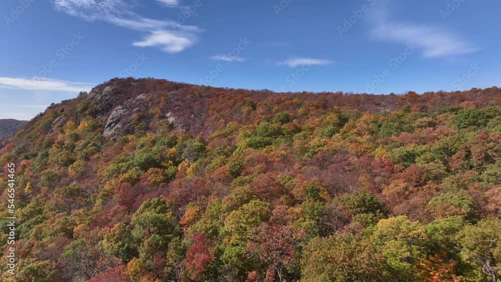 An aerial view above the mountains in upstate NY during the fall foliage changes. Taken on a beautiful day with white clouds. The camera dolly in then pan left above the colorful trees. An aerial view above the mountains in upstate NY during the fall foliage changes. Taken on a beautiful day with white clouds. The camera dolly in then pan left above the colorful trees.