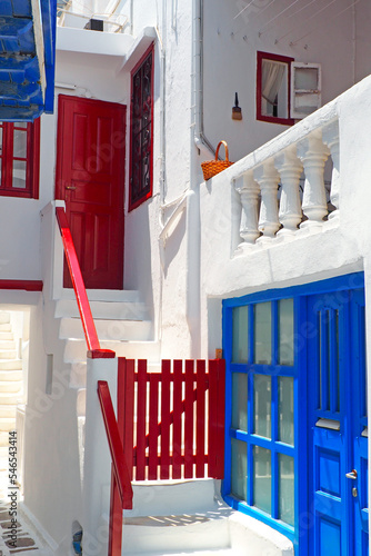 Fototapeta Naklejka Na Ścianę i Meble -  One of the charms of the Greek islands of the Cyclades, in the heart of the Aegean Sea, are the narrow streets lined with white houses with their cobbled stairs and their small flowered balconies