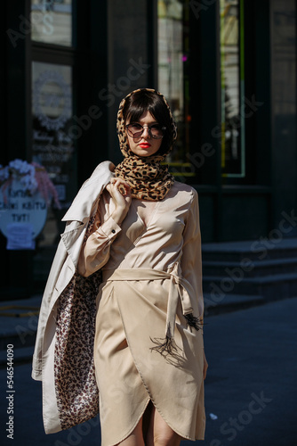 A gorgeous girl in a dress and glasses walks around the city on a sunny day