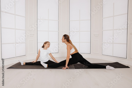 Young mother trainer together with little daughter stretch pilates sport gymnastic exercise
