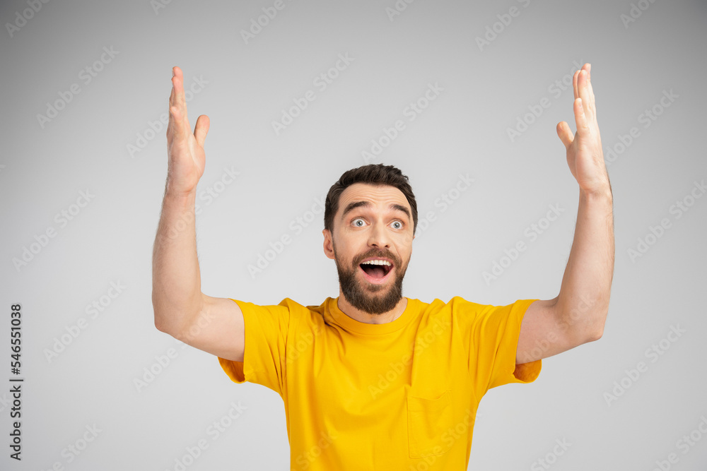 amazed man in yellow t-shirt standing with open mouth and showing wow gesture isolated on grey. amazed man in yellow t-shirt standing with open mouth and showing wow gesture isolated on grey.