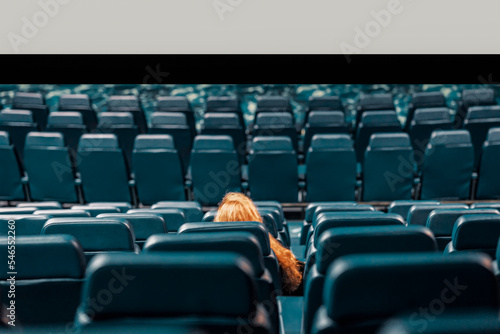Abstract girl, lonely spectator in an empty cinema hall, empty seats