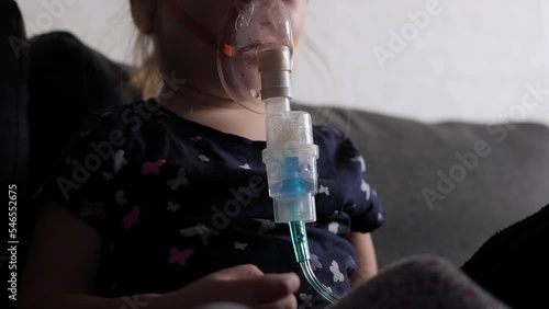 Little girl treatment with inhalation mask on her face at home