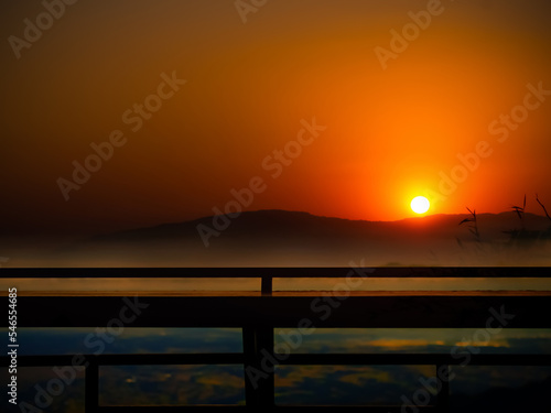 Evening Twilight Gold with Fog and Silhouette Wooden Balcony Beauty Sunlight Orange Cloud Sky Nature Background Reflection Horizon Sunrise with Mountain Landscape Tourism Vacation Travel Holidays.