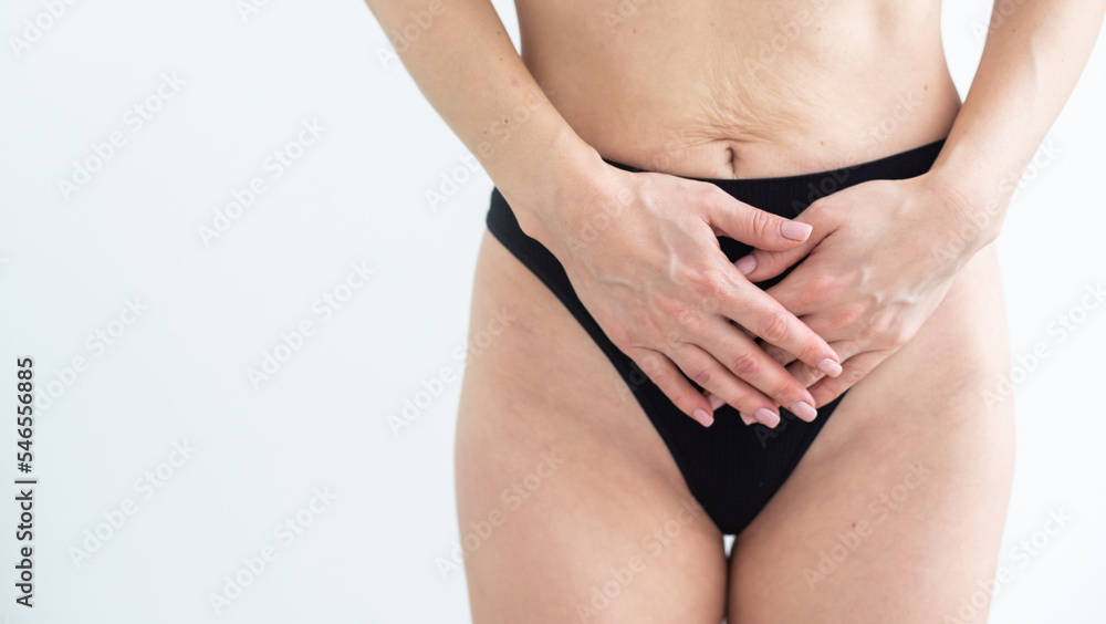 Concept of bodycare gynecology and woman's health. Cropped close up photo of woman's hand touching lower part of her abdomen, isolated on white background.