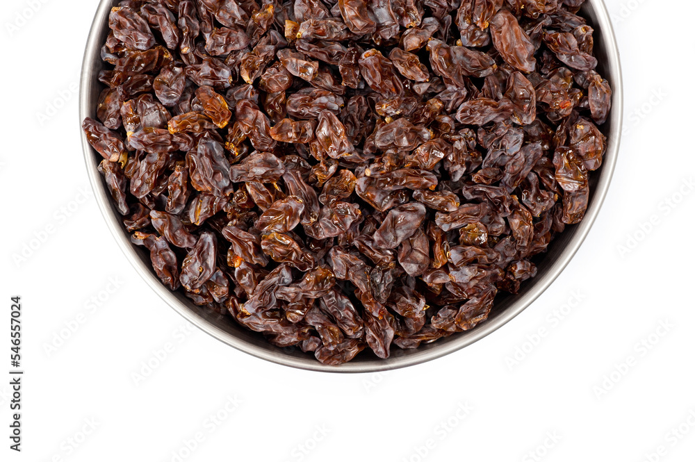 Dark-colored raisins lying in a metal container, shot on a white background. Dark-colored raisins lying in a metal container, shot on a white background.