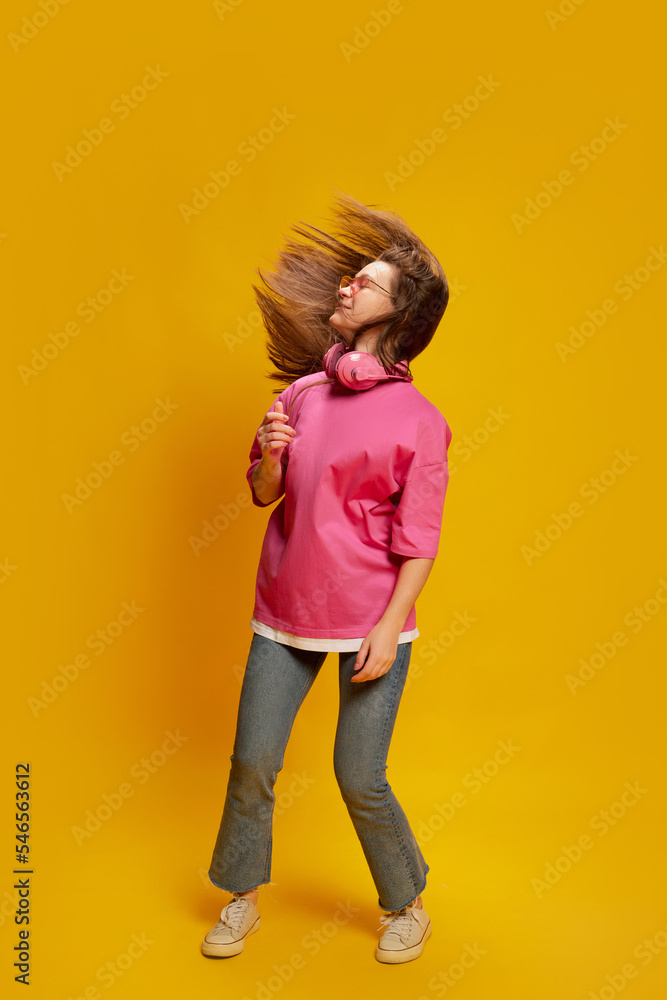 Portrait of young woman in bright casual clothes posing, dancing isolated over yellow background. Concept of youth culture, emotions, Portrait of young woman in bright casual clothes posing, dancing isolated over yellow background. Concept of youth culture, emotions,