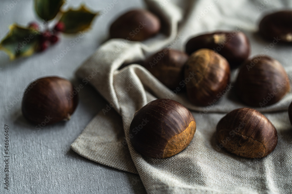 Fototapeta premium Step by step process of making roasted chestnuts. Heap of raw chestnuts on linen cloth.