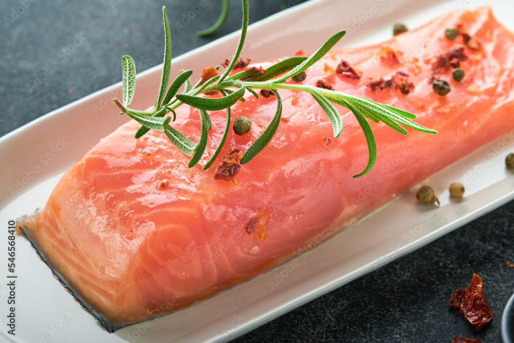 Salmon fish piece. Fresh raw salmon fish piece on marble board stand with herbs and lemon on black background. Seafood or menu concept. Top view. Salmon fish piece. Fresh raw salmon fish piece on marble board stand with herbs and lemon on black background. Seafood or menu concept. Top view.