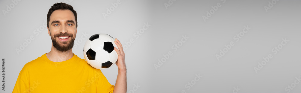 cheerful bearded man in yellow t-shirt holding soccer ball isolated on grey, banner. cheerful bearded man in yellow t-shirt holding soccer ball isolated on grey, banner.