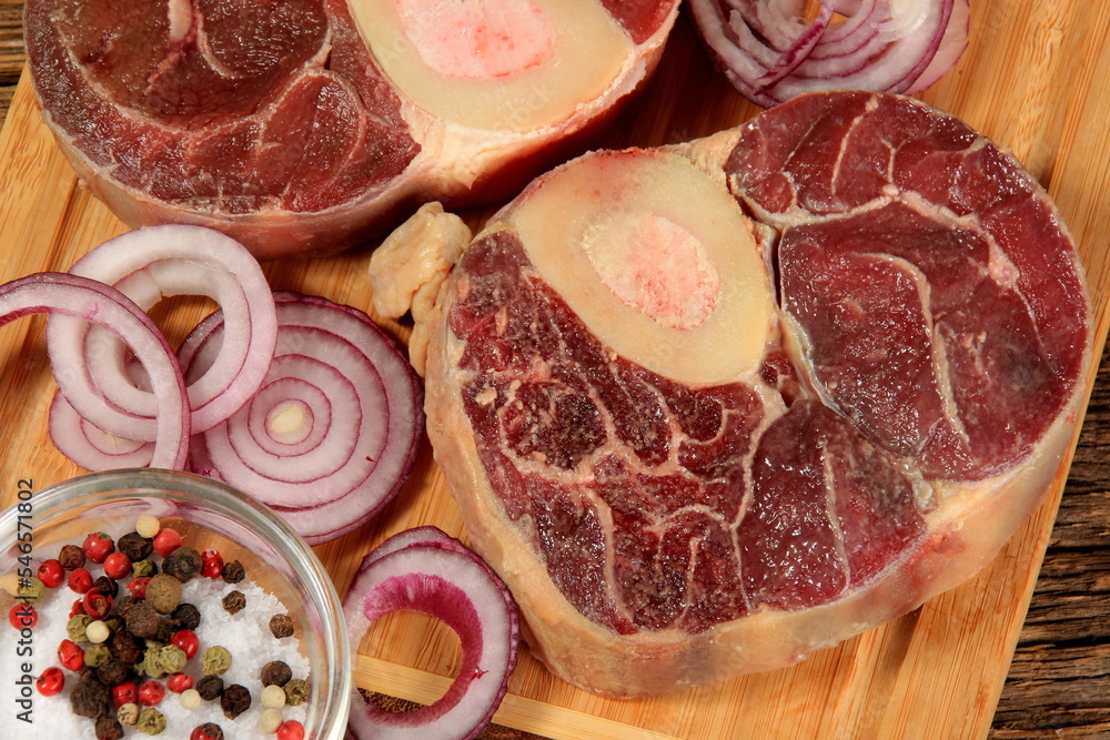 Raw fresh cross cut veal shank, red onion and pepper on kitchen board. Osso Buco on wooden cutting board Raw fresh cross cut veal shank, red onion and pepper on kitchen board. Osso Buco on wooden cutting board