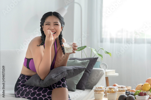 Obraz na płótnie happy beautiful young woman sit on sofa having healthy breakfast at home with fruit and nature yogurt, wellbeing diet concept. w salonie
