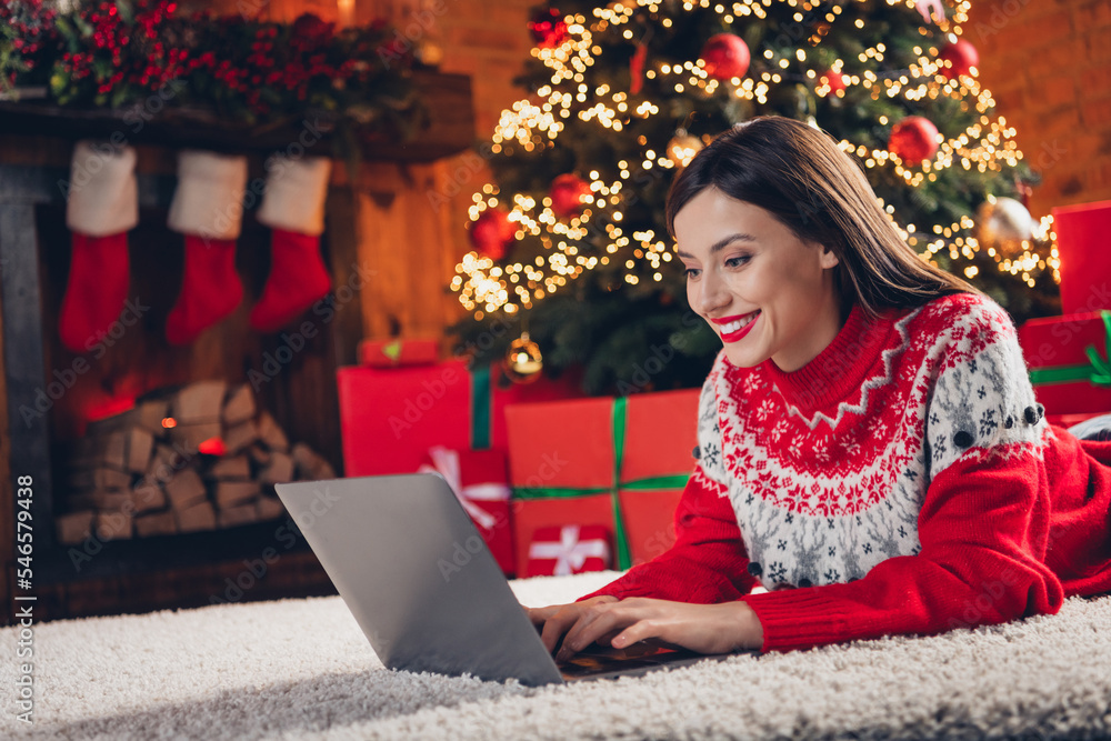Photo of attractive positive girl lay carpet floor use wireless netbook write message email decoration lights indoors Photo of attractive positive girl lay carpet floor use wireless netbook write message email decoration lights indoors