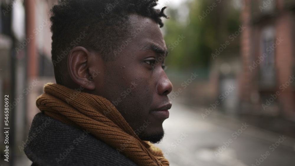 Concerned black man standing outside in city, close-up face portrait thoughtful expression Concerned black man standing outside in city, close-up face portrait thoughtful expression