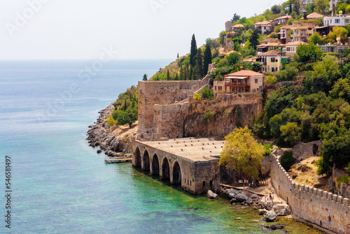 Fototapeta Naklejka Na Ścianę i Meble -  Ancient shipyard (Tersane) near of Kizil Kule tower in Alanya, Turkey (Turkiye) Famous tourist destination with high mountains. Beautiful beach and calm turquoise sea surface. copy space