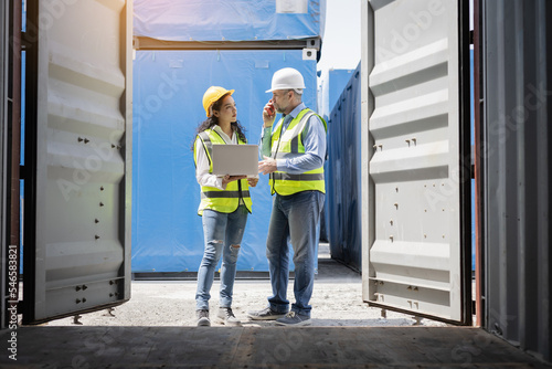 Teamwork man and woman in safety helmet and talking at cargo container. female and male work in dock warehouse export logistic industrial.