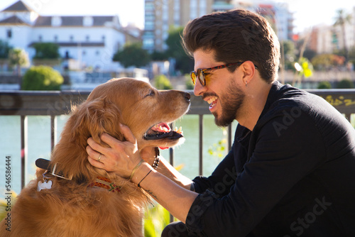 young latino man with sunglasses and beard and his brown golden retriever dog look at each other with love and affection. Concept pets, animals, dogs, love to retriever pets. photo