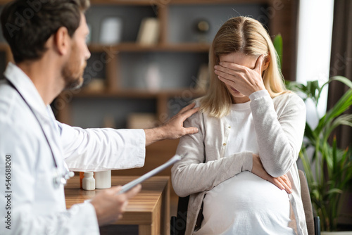 Gynecologist Doctor Comforting Upset Pregnant Woman During Meeting In Clinic