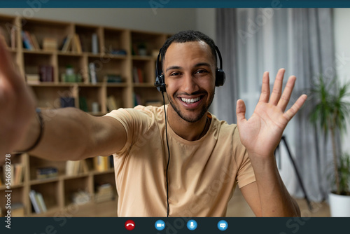 Web conference. Happy arab freelancer man in headset making video call and gesturing hello, monitor screenshot, collage