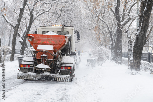 red snowplow clears snow in the city after snowfall