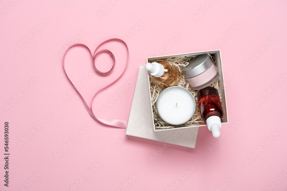 Beauty box with skin care cosmetics and scented candle on pink background with heart shaped ribbon. Gift for Valentine's Day, birthday Beauty box with skin care cosmetics and scented candle on pink background with heart shaped ribbon. Gift for Valentine's Day, birthday