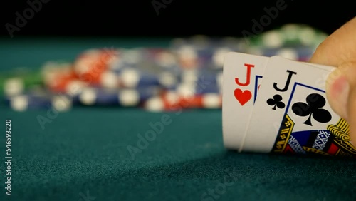 Poker player checks his hand with pair of jacks and raises bet, close-up photo