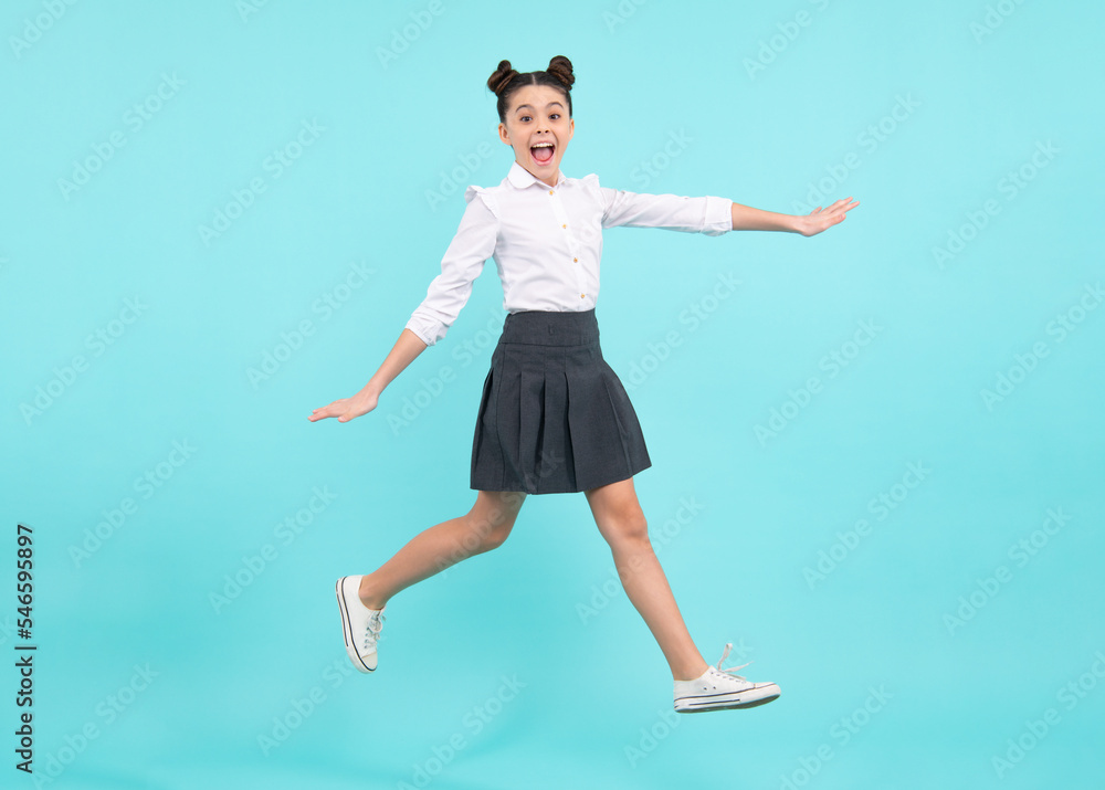 Happy jumping teenager. Happy schoolgirl, positive and smiling emotions of teen girl. Full length jump of teenager girl on blue isolated studio wear casual skirt and shirt.