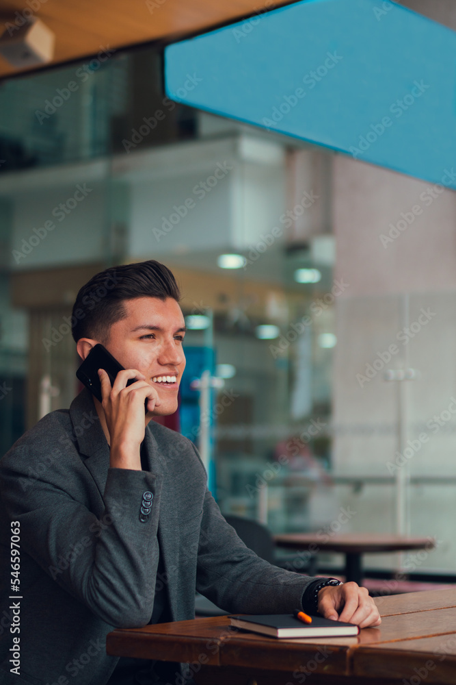 Man talking on cellphone while sitting in cafeteria Man talking on cellphone while sitting in cafeteria