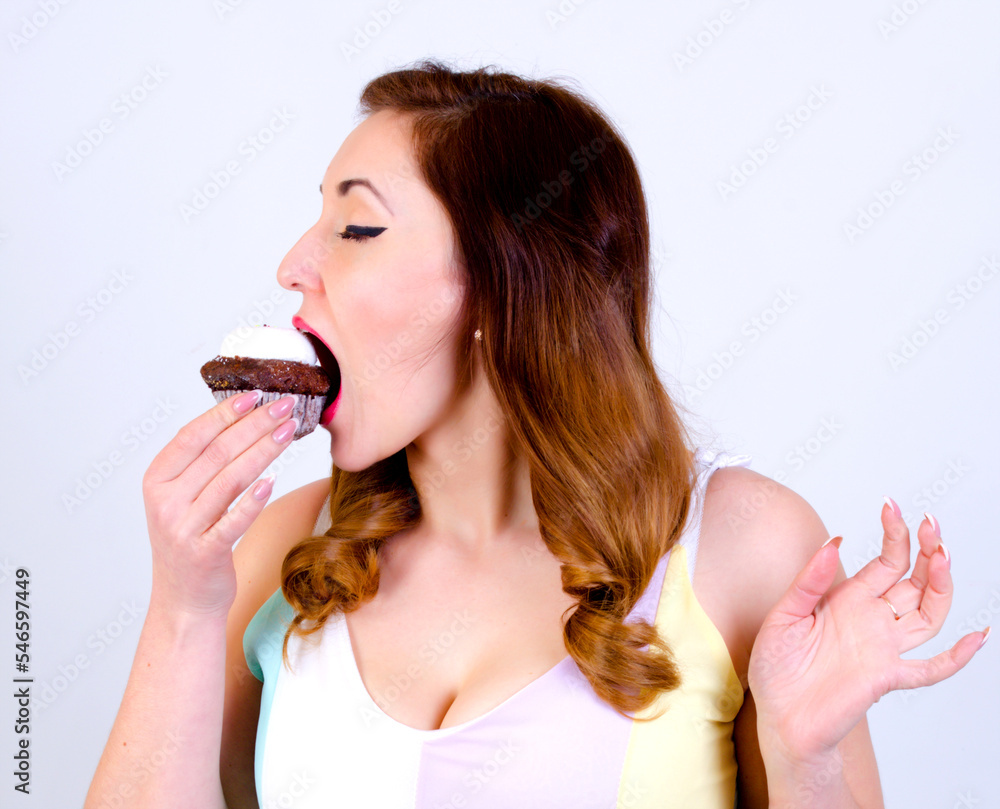 Adult woman eating cupcake on white background