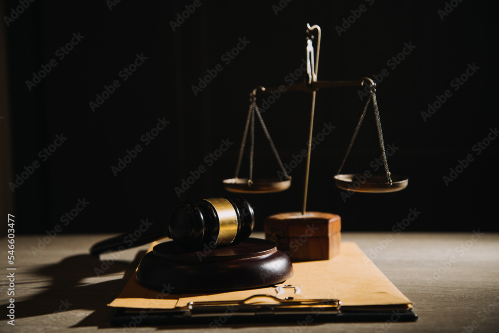 Justice and law concept.Male judge in a courtroom with the gavel, working with, computer and docking keyboard, eyeglasses, on table in morning light