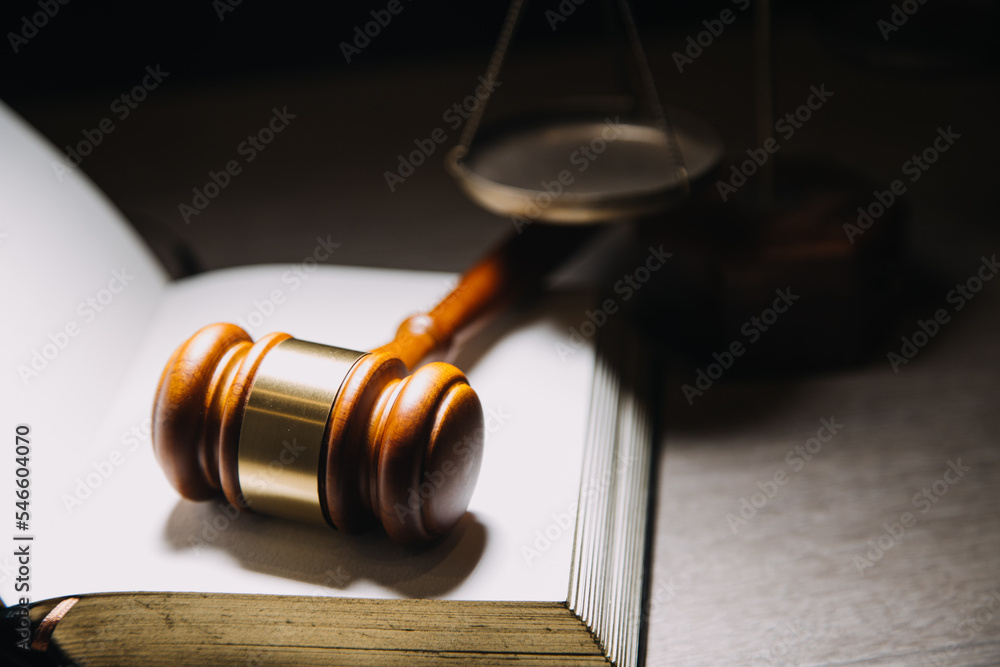 Justice and law concept.Male judge in a courtroom with the gavel, working with, computer and docking keyboard, eyeglasses, on table in morning light Justice and law concept.Male judge in a courtroom with the gavel, working with, computer and docking keyboard, eyeglasses, on table in morning light