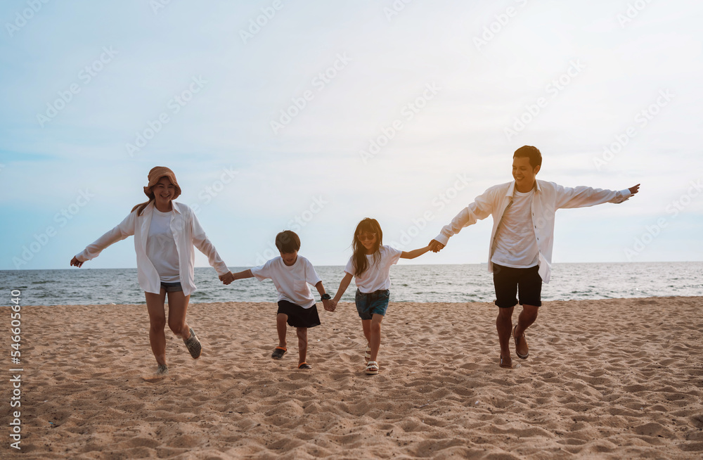 Happy asian family enjoy the sea beach at consisting father, mother,son and daughter having fun playing beach in summer vacation on the ocean beach. Happy family with vacations time lifestyle concept. Happy asian family enjoy the sea beach at consisting father, mother,son and daughter having fun playing beach in summer vacation on the ocean beach. Happy family with vacations time lifestyle concept.