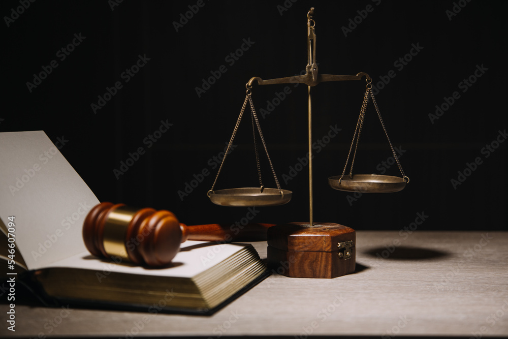 Justice and law concept.Male judge in a courtroom with the gavel, working with, computer and docking keyboard, eyeglasses, on table in morning light