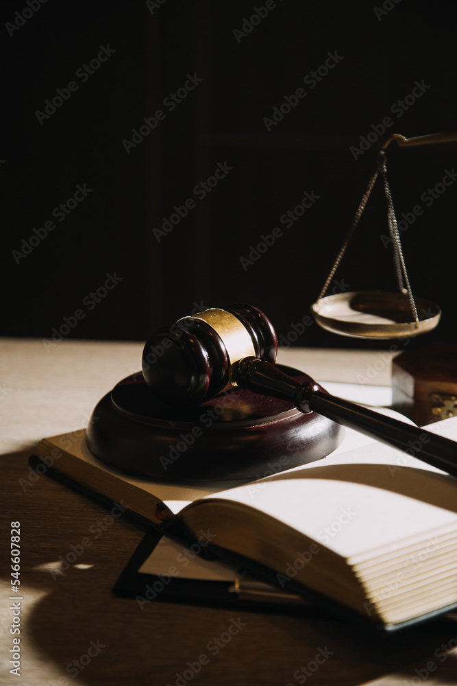 Justice and law concept.Male judge in a courtroom with the gavel, working with, computer and docking keyboard, eyeglasses, on table in morning light Justice and law concept.Male judge in a courtroom with the gavel, working with, computer and docking keyboard, eyeglasses, on table in morning light