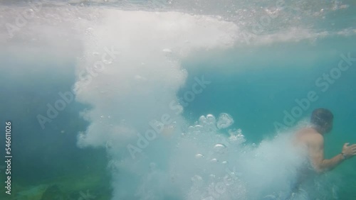 Unrecognizable person enters the water headfirst in slow-mo