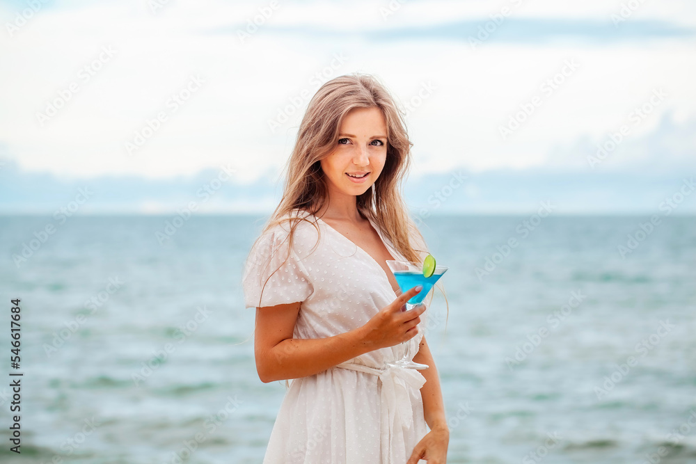 Woman with cocktail by the sea looking at camera Woman with cocktail by the sea looking at camera