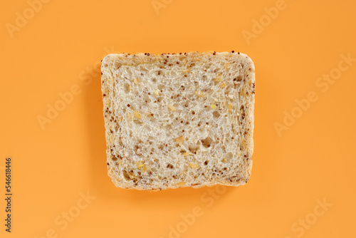 A slice of vegan whole grain bread on orange background