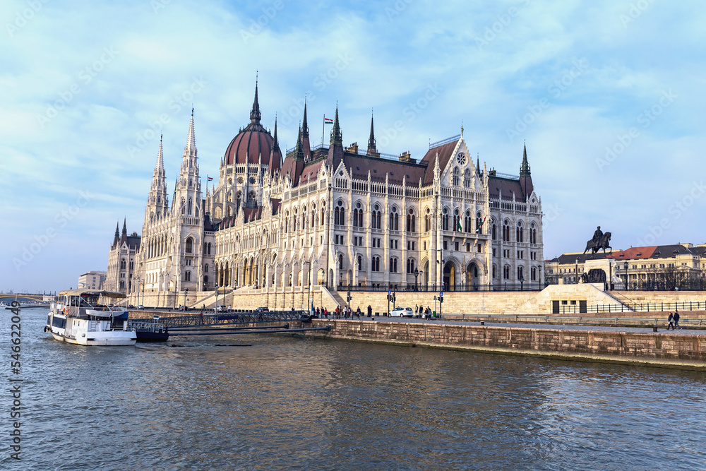 Fototapeta premium View from the Danube River to the Gothic building of the Hungarian Parliament and a tourist ship at the pier