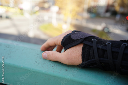 hand with a black wrist splint on a handrail.
