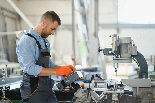 Manual worker cutting aluminum and PVC profiles. Manufacturing jobs. Selective focus. Factory for aluminum and PVC windows and doors production.