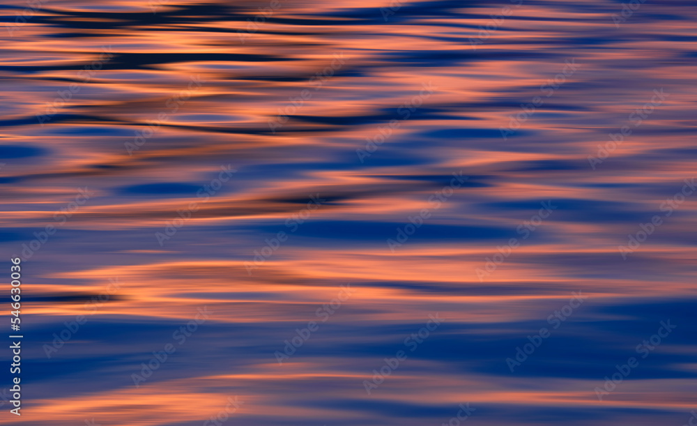 Background abstract colorful motion blur of ripples with dusk sky reflection on sea surface after sundown