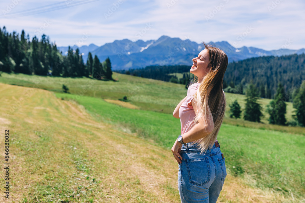 back view of girl with closed eyes and long hair on the meadow o