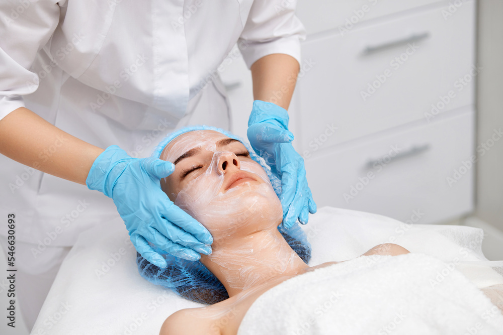 beautician applies the mask to the face of beautiful woman beautician applies the mask to the face of beautiful woman