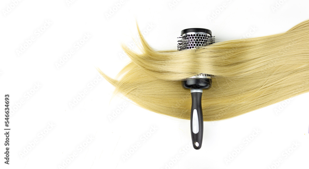 Fototapeta premium Round brush combs with long blond hair closeup. Round hair brush with highlight hair in it.