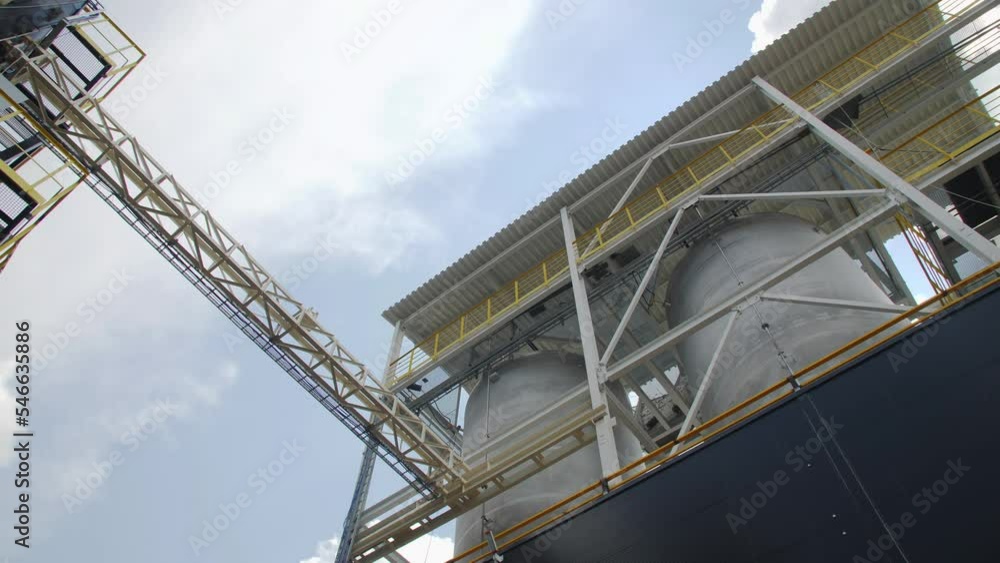 Large tanks with service ground and pipes at chemical manufacturing plant under sky low angle shot. Reservoirs for products Large tanks with service ground and pipes at chemical manufacturing plant under sky low angle shot. Reservoirs for products