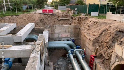 Laying hot water pipes right in the middle of the road. A pit has been created on the road for carrying new plumbing pipes. Underground pipeline repair.